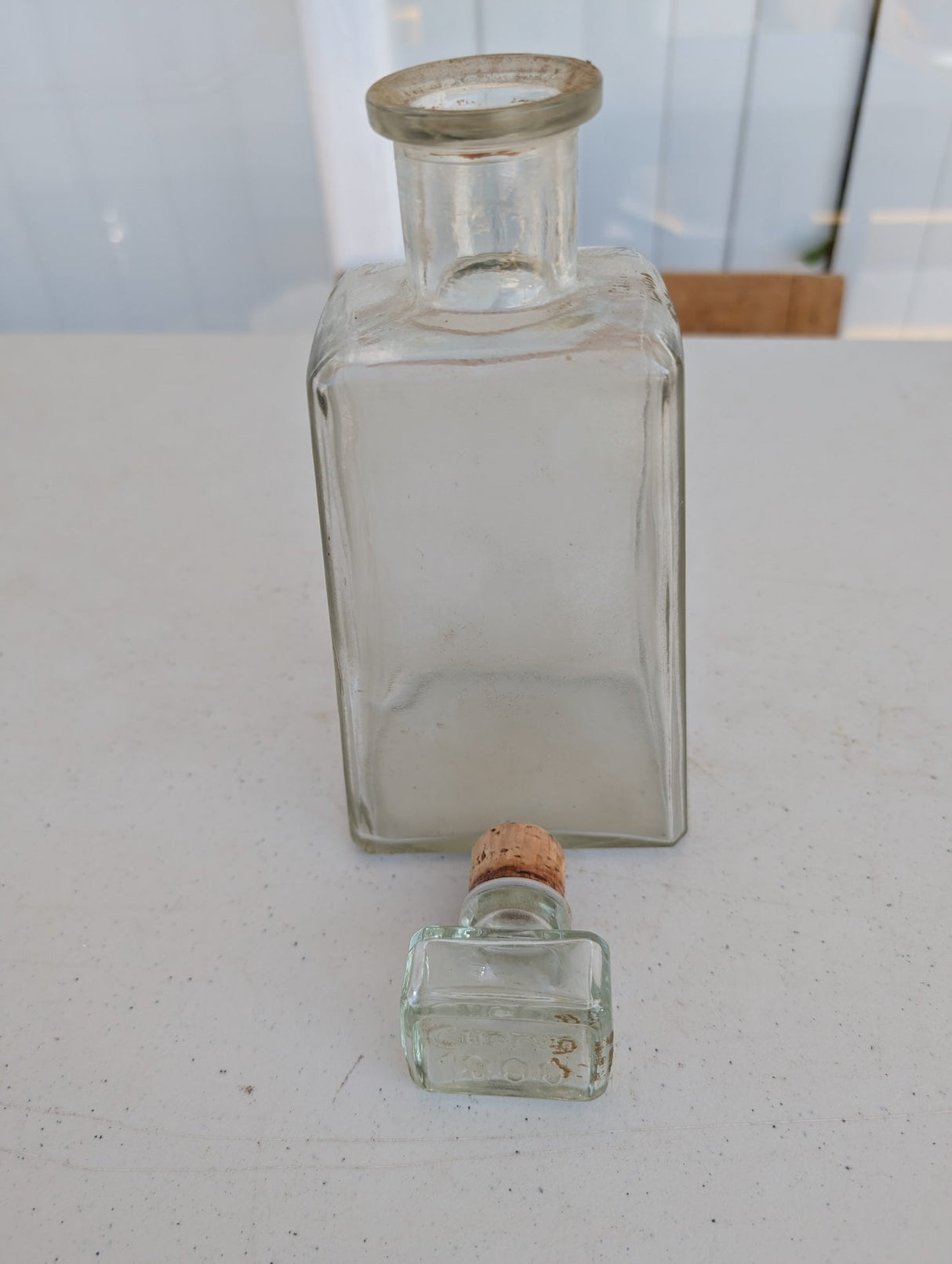 Botella de alcohol de vidrio con tapón, antigua, hecha a máquina.